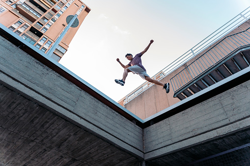 Talented young man practicing parkour tricks in the city and having fun.