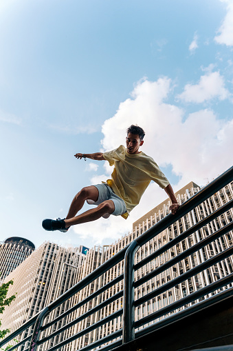 Concentrated cool man practicing parkour tricks in the city and having fun.