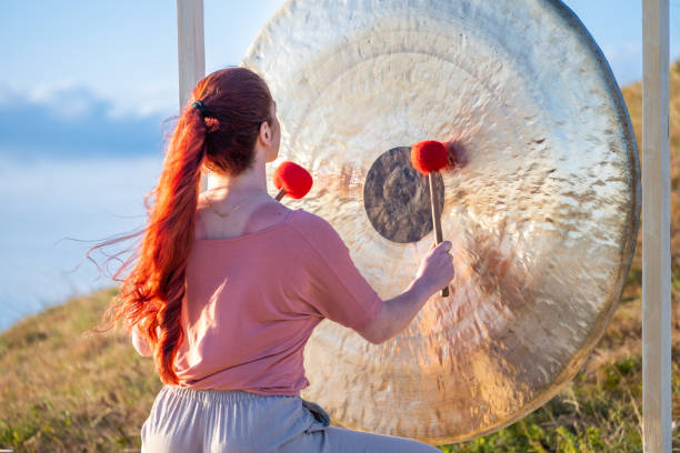 istock Sound meditation therapy, woman playing bronze gong, back view 1440215559