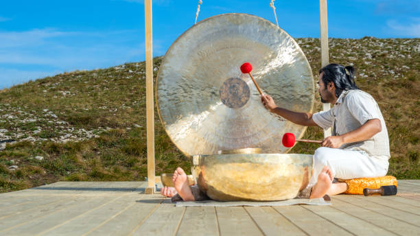istock Sound therapy, man hitting bronze gong, wide shot 1440215569