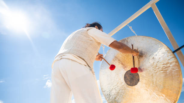 istock Man playing bronze gong with drumsticks, low angle view 1440215594