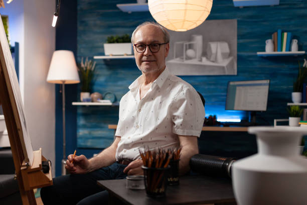 portrait d’un vieil homme inspiré posant confiant tenant un crayon dans un studio d’art professionnel - romania men artist portrait photos et images de collection