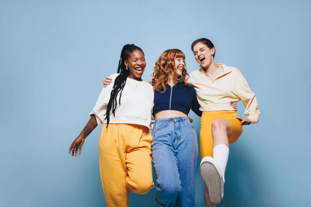 Group of cheerful female friends having fun together in a studio Group of cheerful female friends having fun while embracing each other. Three happy young women laughing and having a good time while standing against a studio background. three amigos stock pictures, royalty-free photos & images