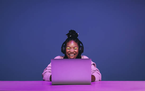 веселая женщина-геймер выигрывает онлайн-игру на ноутбуке - youth culture audio стоковые фото и изображения