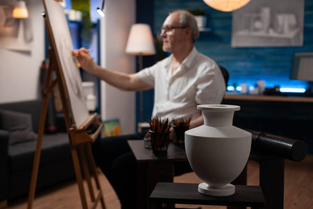 vaso modello bianco sul tavolo di legno utilizzato per lo studio della luce dal disegno dell'artista dell'uomo in pensione usando la matita affilata - romania men artist portrait foto e immagini stock