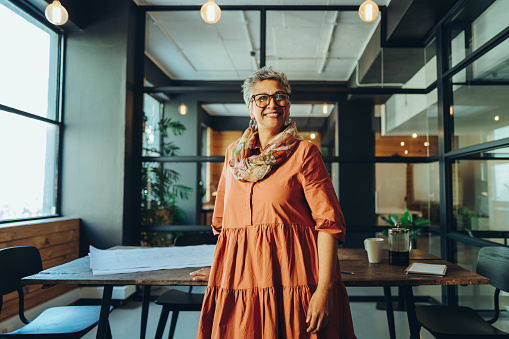 Happy mature businesswoman smiling at the camera while standing in an office. Cheerful mature businesswoman standing in the boardroom of a modern workplace.