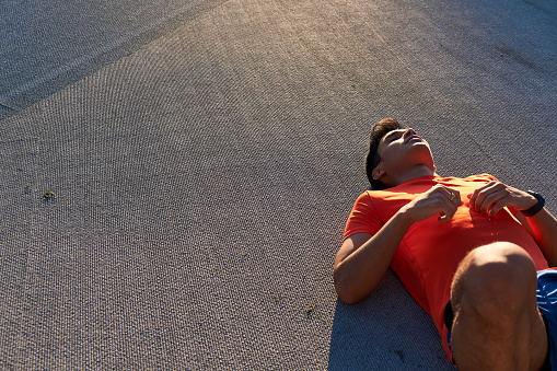 Young sportsman resting on the floor after doing sit-ups. With copy space