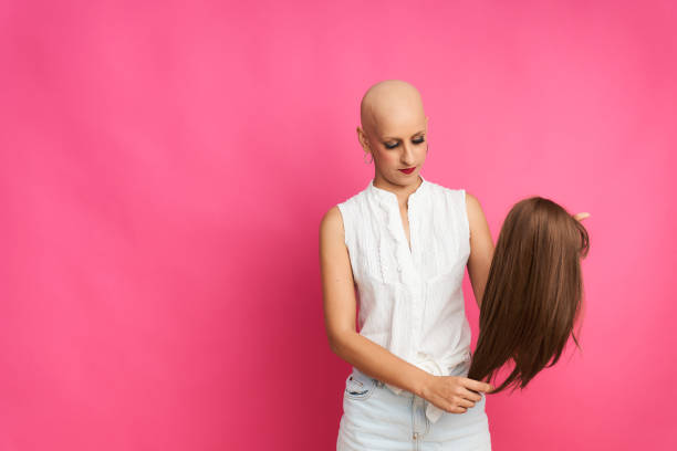 portrait of a woman suffering from breast cancer preparing the wig to cover her head without hair stock photo