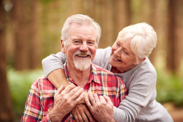 Portret kochającej emerytowanej pary seniorów przytulającej się na spacerze po leśnej wsi razem – zdjęcie