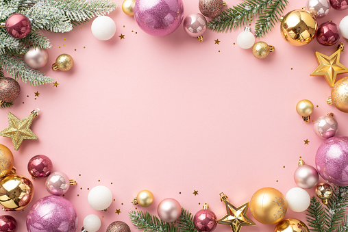 Christmas decorations concept. Top view photo of stylish white gold and pink baubles star ornaments confetti and pine branches in snow on isolated light pink background with copyspace in the middle
