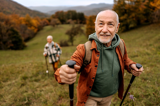 Senior man on a hike with his wife behind him