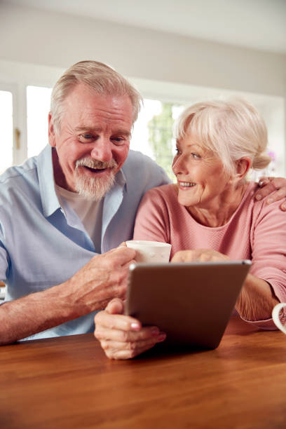 istock Retired Senior Couple Sitting In Kitchen At Home Drinking Coffee And Using Digital Tablet 1440225117