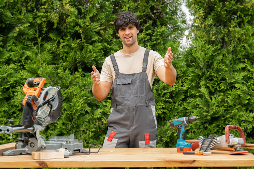 Carpenter using camcorder in workshop. Caucasian male craftsperson with camera, recording DIY tutorial.