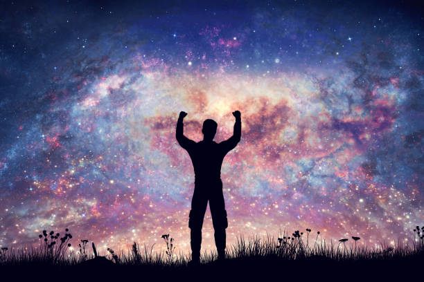 istock Happy man with hands up on night sky with nebula and stars 1440227255