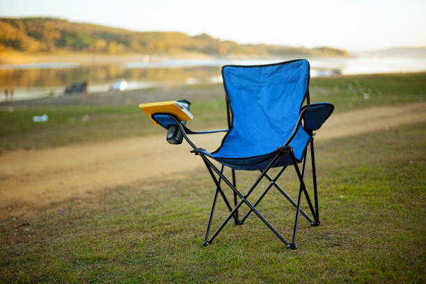 istock Camping chair and coffee thermos by the lakeside 1440229832