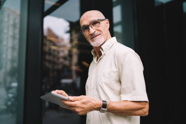 istock Content aged man with tablet standing on street 1440237922