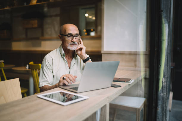 istock Thoughtful senior businessman working on laptop in cafe 1440238034