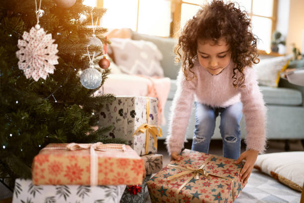 istock Girl, placing Christmas presents under the Christmas tree 1440238731