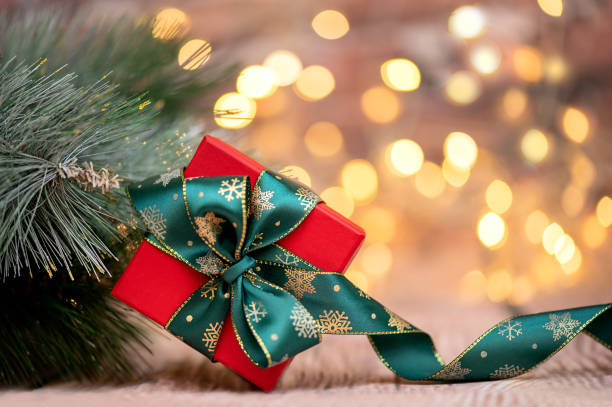 istock Red Christmas gift box with green ribbon on blurred lights background 1440241319