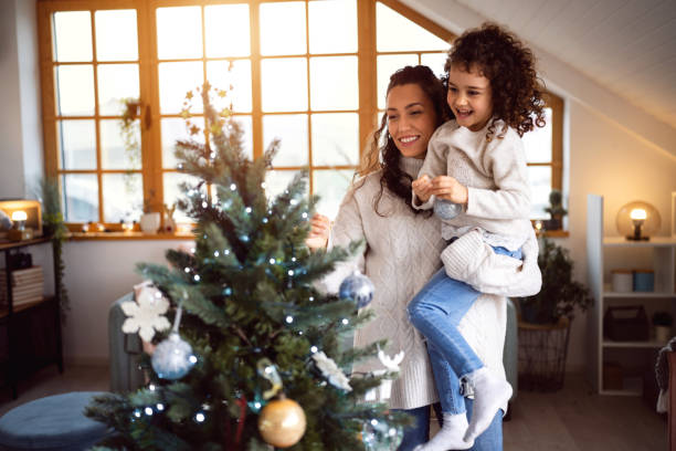 istock Mother and daughter decorating Christmas tree 1440241347