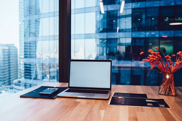 Laptop and smartphone on wooden table with documents in workplace