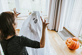 ハロウィーンの幽霊の衣装を作る日本の母と息子