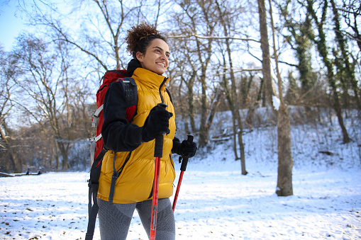 Young woman hiking in nature during winter. About 25 years old mixed-race female.