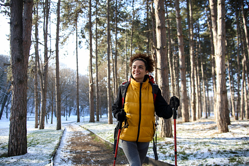 Young woman hiking in a mountain forest during winter. About 25 years old mixed-race female.