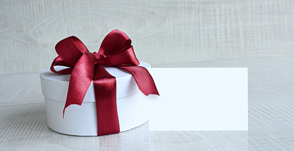 Round gift boxe with red ribbon and bow on grey background.