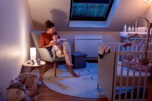Same-sex female couple puts baby to sleep in nursery room