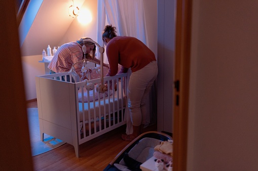 Same-sex female couple puts baby to sleep in nursery room