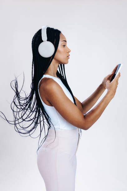 vista laterale di una giovane donna che sceglie una playlist audio sul suo telefono - spanish culture audio foto e immagini stock