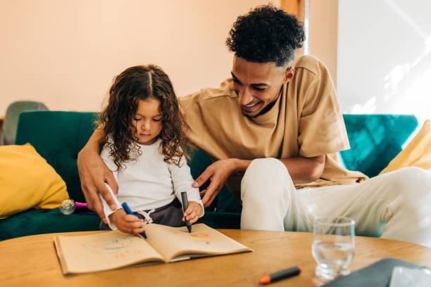 istock Cheerful single father teaching his daughter how to draw in a colouring book 1440258696