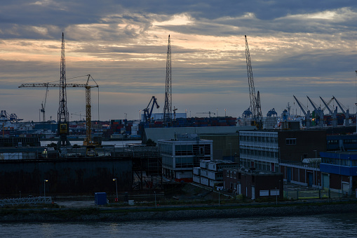 Early evening skyline in the Dutch port of Rotterdam in The Netherlands,  Northern Europe, showing silhouetted cranes of the industrial working port