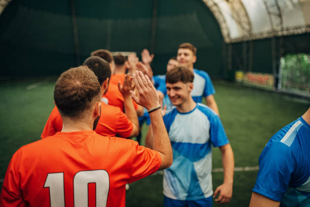Large group of men, male soccer players sharing sportsmanship on the soccer field indoors after they played a match.