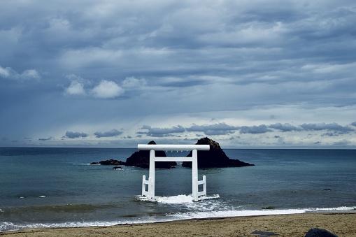 A wide shot of Itoshima beach in Fukuoka, Japan during twilight with white torii gate in the center