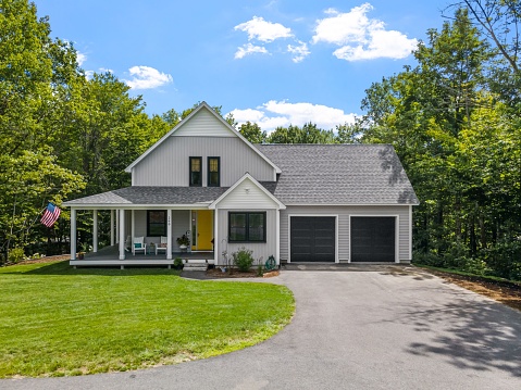 A modern custom new England colonial home with an American flag on a sunny day