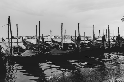 A black and white shot of gondolas docked in the water