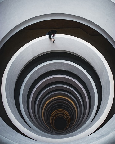 A beautiful overhead shot of a spiral staircase with a photographer taking a shot from the opening