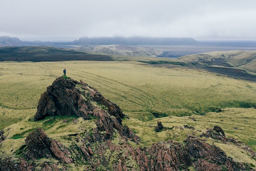 An aerial shot of a caucasian man on the green-covered mounts in the Katla Geopark, Iceland