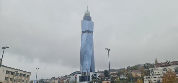 Sarajevo, Bosnia and Herzegovina – November 06, 2022: A low-angle of Avaz Twist tower in Sarajevo against gloomy, cloudy sky, cityscape around