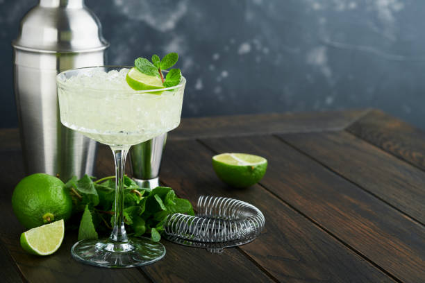 istock Margarita cocktail with lime, tequila, mint and ice on dark table with amazing backlight, copy space. Classic Margarita or Daiquiry Cocktail. Bar card or counter concept. Selective or soft focus. 1440267075