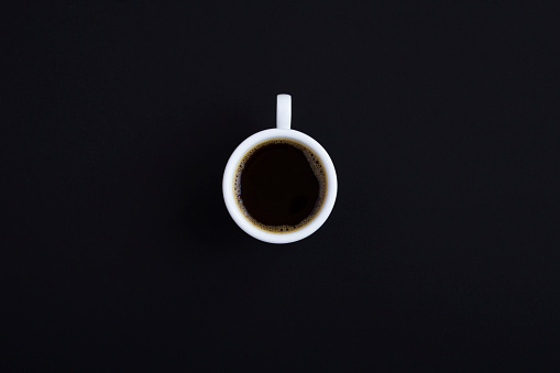 Cup of black coffee on the black background. Top view. Copy space.