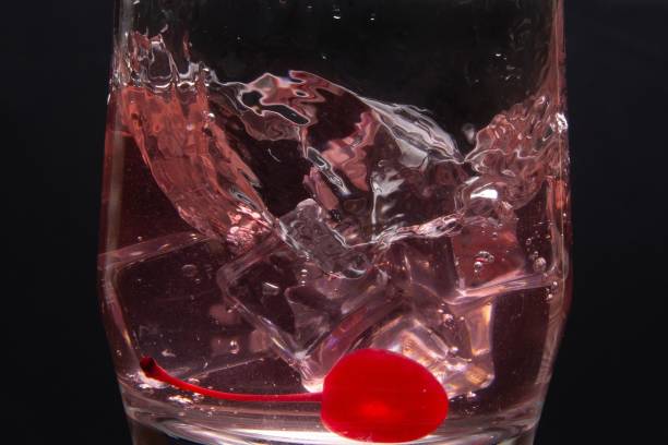 Splashing into a drink filled with ice in a glass cup on black background