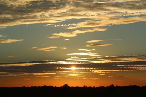 istock Glimpse of sunlight shinning through scattered clouds in a sunset sky 1440267641