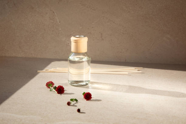 istock Aroma diffuser in a clear glass bottle with a wooden cap on a light stone background with wooden sticks behind and red chrysanthemum flowers 1440269845