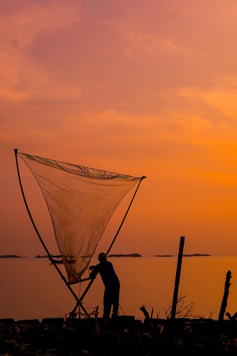 Fisherman at the dock with his fishing net enjoying the sunset