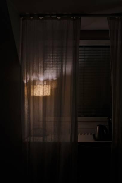 istock A dim lamp behind a transparent curtain on a windowsill 1440271889