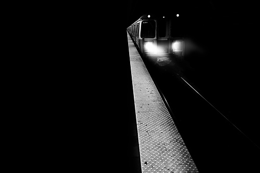 A train with lights on moving forward shot in black and white