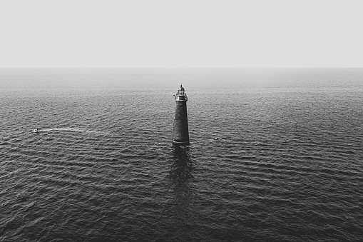 A light tower in the middle of the sea shot in black and white